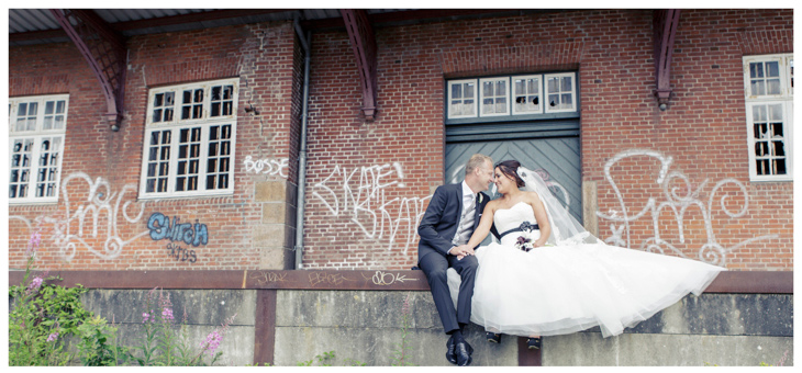 brudepar sidder ved nedlagt banegård foran grafittimalet væg